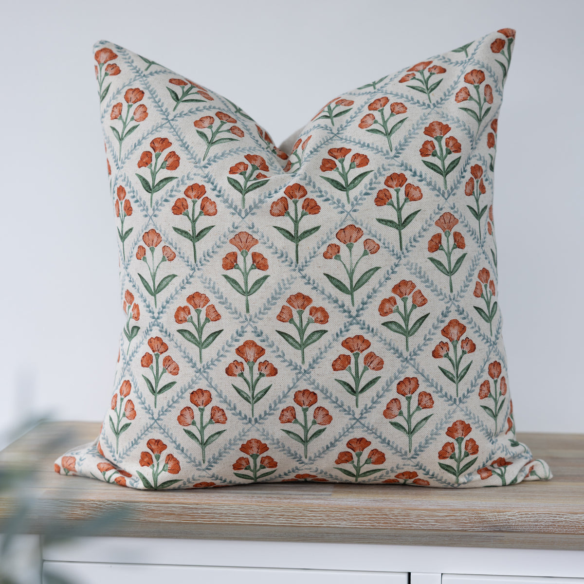 Chatsworth Ginger Floral Cushion with orange flowers, green leaves and pale blue trellis on cream